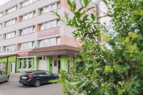 a building with cars parked in front of it at CITY HOTEL Družba in Liptovský Mikuláš