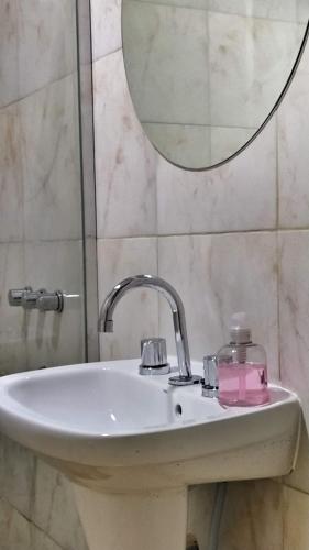 a bathroom sink with a mirror and a pink soap dispenser at Saenz Peña x 4 in Venado Tuerto