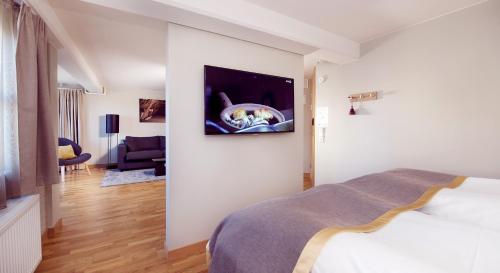 a bedroom with a bed and a tv on a wall at Home Hotel Bryggeparken in Skien