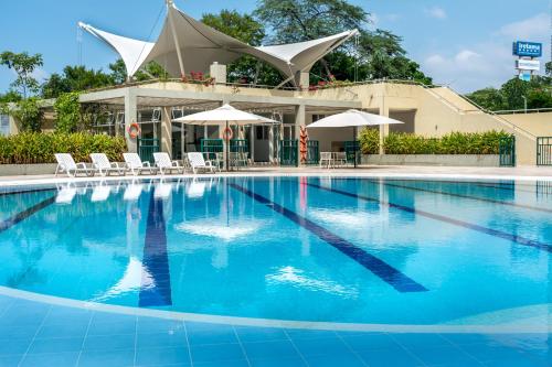 a large swimming pool with chairs and umbrellas at Apartamento - Condominio Zazué in Santa Marta