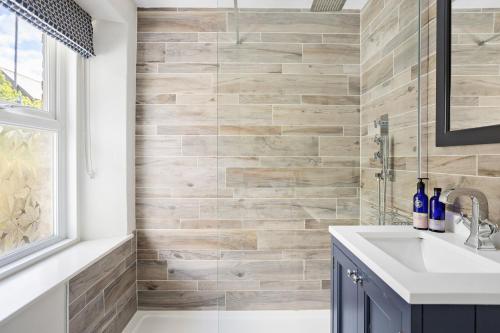 a bathroom with a sink and a tile wall at The Old Shop House in Galmpton-on-the-Dart