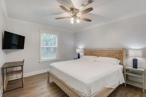um quarto com uma cama branca e um ventilador de teto em The Swamp Rose Cottage em Bay Saint Louis
