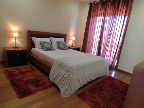 1 dormitorio con 1 cama con 2 lámparas y 2 alfombras en Casas Solar da Torre en Navais