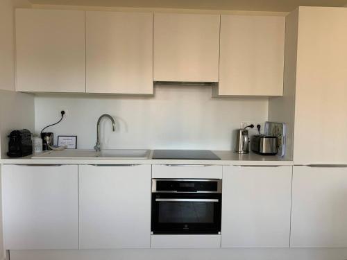 une cuisine avec des armoires blanches et un four noir dans l'établissement Two bedroom apartment Rouaze, à Cannes