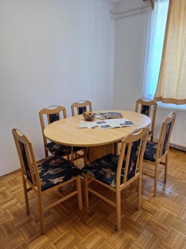a dining room table with chairs and a wooden floor at Župnijski apartmaji in Dolenjske Toplice