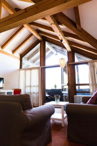 a living room with couches and a large window at Gästehaus Rössler in Brannenburg