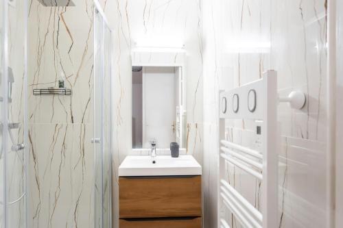 une salle de bain blanche avec un lavabo et un miroir dans l'établissement #58 Logement Clim & Balcon 5mins marche de la Mer, à Nice