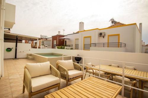 a balcony with a table and chairs and a house at Luxuosa Villa com Piscina, Garagem e Vista Mar in Tavira