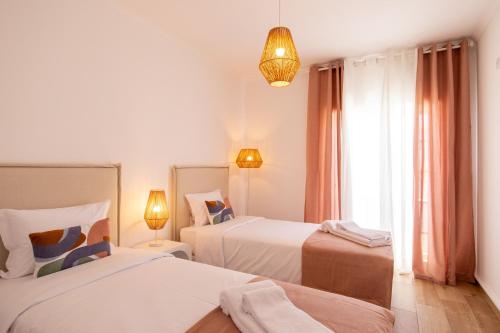 a white room with two beds and a window at Luxuosa Villa com Piscina, Garagem e Vista Mar in Tavira