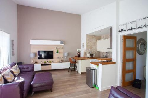 a living room with a purple couch and a kitchen at Mosspark Boulevard Exec Apartment ii - Free Parking in Glasgow