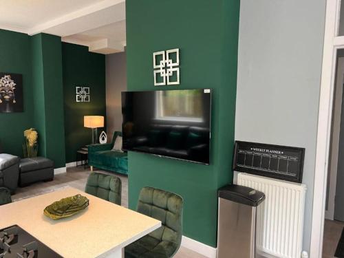 sala de estar con pared verde y TV de pantalla plana en Loch Lomond Mews, en Balloch