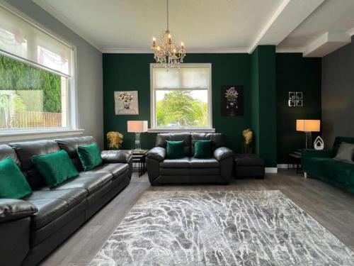 sala de estar con sofá y paredes verdes en Loch Lomond Mews, en Balloch