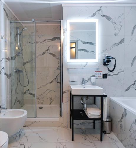 a bathroom with a shower and a sink and a tub at Hotel Filmar in Toruń