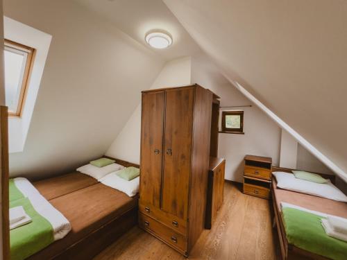 a attic room with two beds and a wooden cabinet at Majláthova Chata Popradské Pleso in Vysoké Tatry