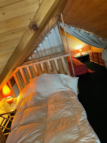 un lit dans une chambre avec un plafond en bois dans l'établissement Le chalet sur le toit, à Briançon