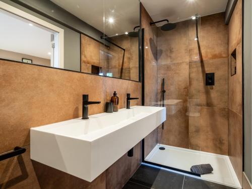 a bathroom with a white sink and a shower at Farmyard House in Amlwch