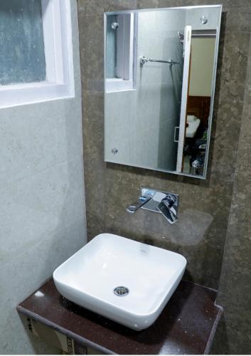 a bathroom with a white sink and a mirror at Hotel Raghunath in Jammu