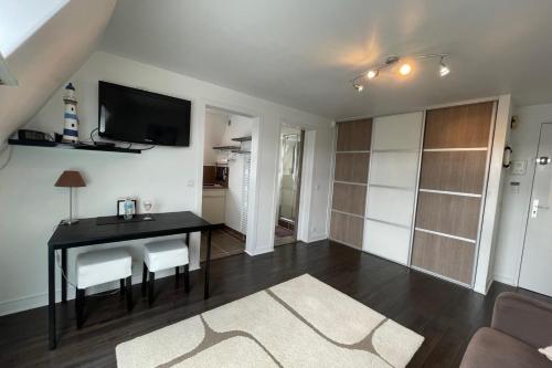 un salon avec une table et une télévision au mur dans l'établissement T1 comfort with nice open view, à Trouville-sur-Mer