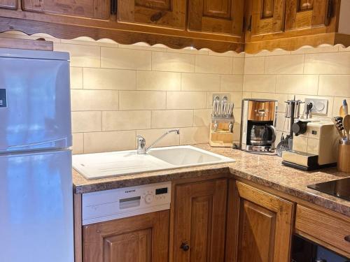 une cuisine avec un évier et un réfrigérateur blanc dans l'établissement Charmant appart 4 pers, proche pistes et centre, terrasse 30m², parking, équipements complets - FR-1-623-306, aux Gets