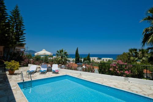 una piscina con 2 sillas y vistas al océano en Amalia Villa, en Polis Chrysochous