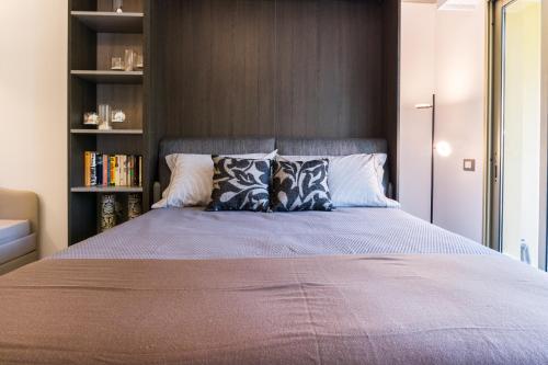 - une chambre avec un lit doté d'oreillers et d'une étagère à livres dans l'établissement Isola Bella by Connexion, à Cannes