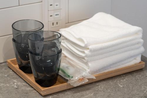a tray with towels and glasses on a counter at THE TANADA SAUNA サウナ 露天風呂 棚田一望 Refaシャワードライヤー in Sakai
