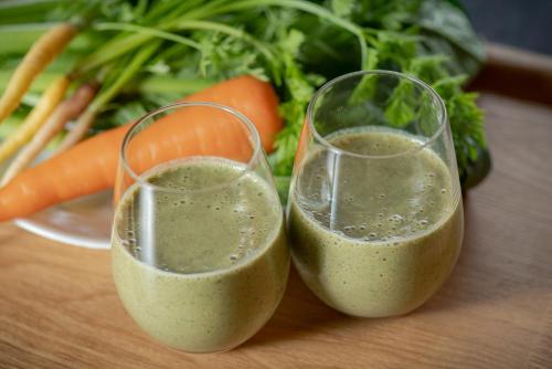 two glasses of green smoothies on a table with vegetables at THE TANADA SAUNA サウナ 露天風呂 棚田一望 Refaシャワードライヤー in Sakai