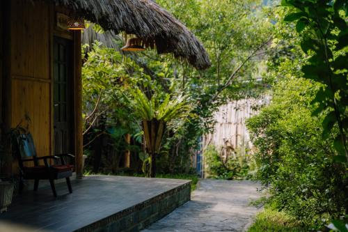a porch of a house with a bench and trees at Ha Giang Xanh Retreat - Trekking, Tour, Motorbike Rental in Ha Giang