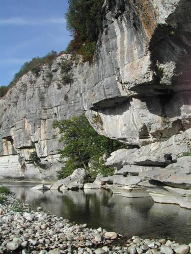 a large rocky mountain next to a body of water at Gîte du Ranc de Figère in Labeaume
