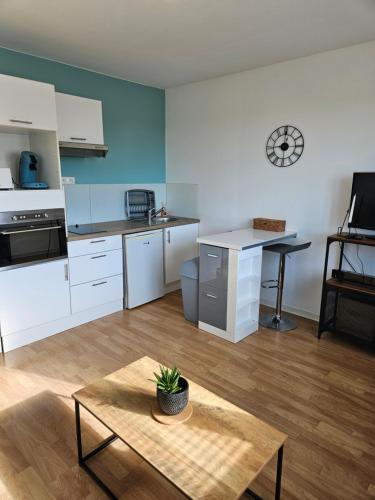 une cuisine avec des armoires blanches et une table dans une pièce dans l'établissement Studio cozy proche Versailles, à Toussus-le-Noble