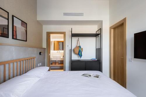 a bedroom with a white bed and a bathroom at Tayo Studios & Apartments in Bat Yam