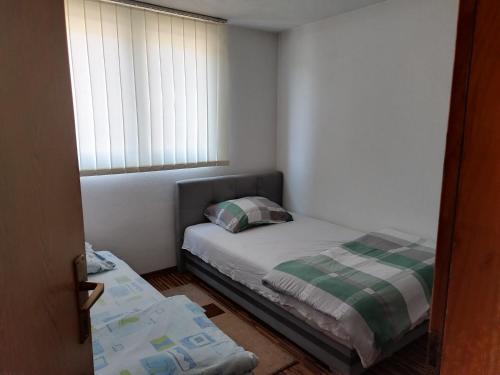 a small bedroom with a bed and a window at Apartman Leki in Sarajevo