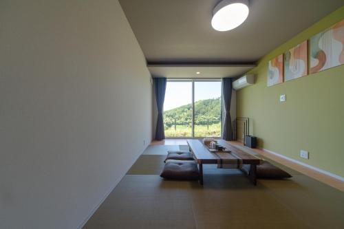 a living room with a table and a large window at THE TANADA SAUNA サウナ 露天風呂 棚田一望 Refaシャワードライヤー in Sakai