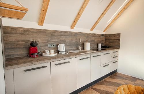 a kitchen with white cabinets and a wooden wall at Family Resort Plitvice Lakes in Rastovača