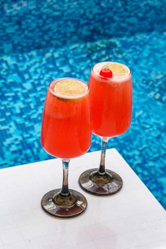 two red cocktails sitting next to a swimming pool at Hotel Virrey Cartagena in Cartagena de Indias