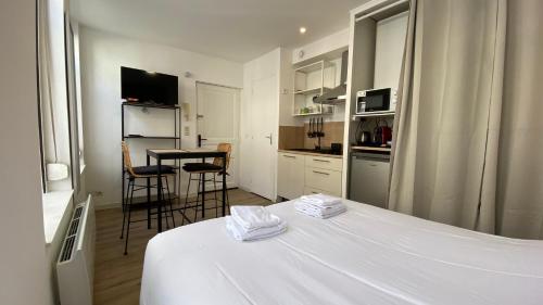 - une chambre avec un lit blanc, une table et des chaises dans l'établissement Nestor - Studio rénové Vieux Lille Esplanade -, à Lille
