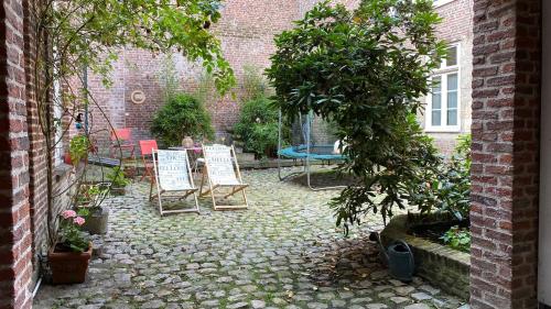 une terrasse avec des chaises, une table et des arbres dans l'établissement Nestor - Studio rénové Vieux Lille Esplanade -, à Lille