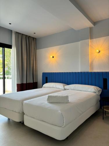 two beds in a bedroom with two lamps on the wall at Apartamentos Sofía in Es Cana