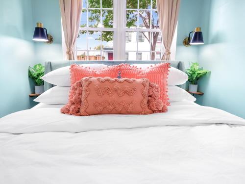 a pink pillow on a white bed with a window at Traveler's Dream - Free Parking near Forsyth Park in Savannah