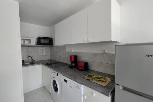 une cuisine avec des armoires blanches et une machine à laver dans l'établissement Cozy on the port, à Frontignan