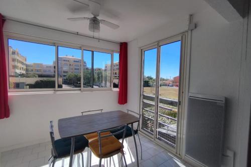 une salle à manger avec une table, des chaises et des fenêtres dans l'établissement Cozy on the port, à Frontignan