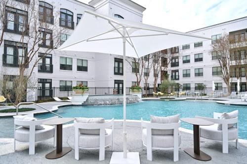 a table and chairs and an umbrella in front of a pool at UBP - Brand New Midtown Montrose 1 Bd Apt in Houston