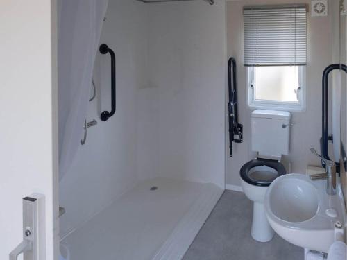 a white bathroom with a toilet and a sink at Pinewoods Easy Access sleeps 6 – dog friendly in Wells next the Sea