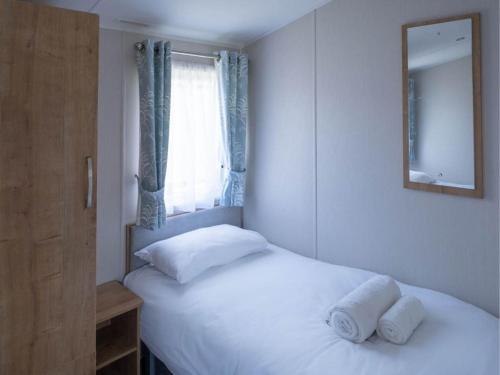 a bedroom with two beds and a mirror and a window at Pinewoods Easy Access sleeps 6 – dog friendly in Wells next the Sea