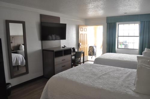 a hotel room with two beds and a mirror at Baymont by Wyndham Fort Stockton in Fort Stockton