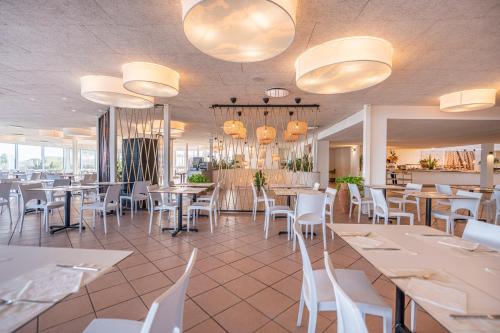 a restaurant with tables and white chairs and lights at Mangia's Pollina Resort in Cefal&ugrave;