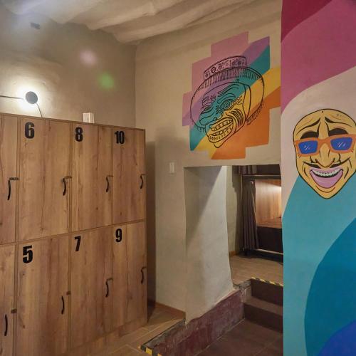 a room with wooden lockers and a painting on the wall at Way Kap Hostel Cusco in Cusco