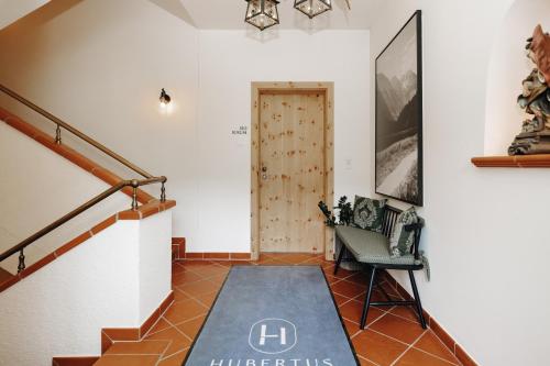 a hallway with a staircase with a door and a chair at Hubertus - Das Landhaus in Kleinarl