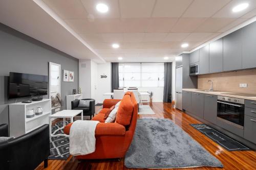 a living room with an orange couch and a kitchen at Vivienda ideal para familias en San Sebastián in Donostia-San Sebastián