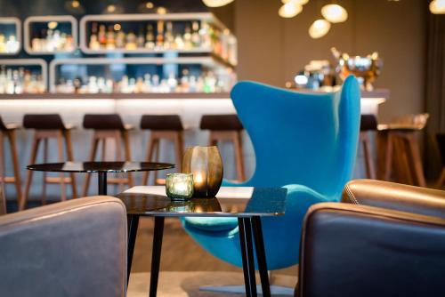 a bar with two tables and a blue chair at Motel One Frankfurt Airport in Frankfurt/Main